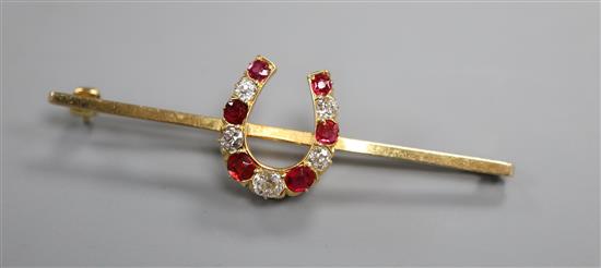 A modern 9ct gold, ruby and diamond set horseshoe bar brooch, 57mm.